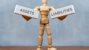 ALM pressures, AI costs test Asia-Pacific insurers’ growth plans: S&P conference Wooden mannequin holds signs labelled “ASSETS” and “LIABILITIES”.