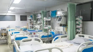 Hospital ward with multiple beds, monitors, infusion pumps and privacy curtains.