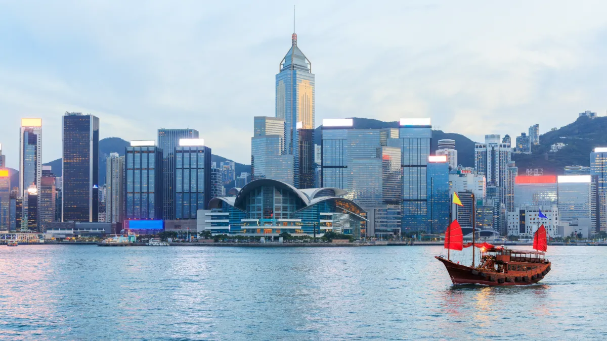 Hong Kong skyline across Victoria Harbour, with the Convention and Exhibition Centre and a traditional junk boat.