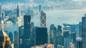 Hong Kong skyline and Victoria Harbour viewed from above, featuring dense high-rise buildings and the Bank of China Tower.