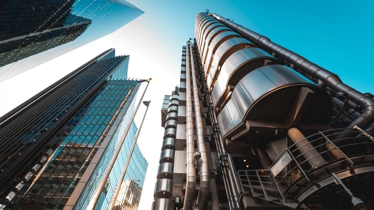Lloyd’s of London building and surrounding glass skyscrapers viewed from street level.