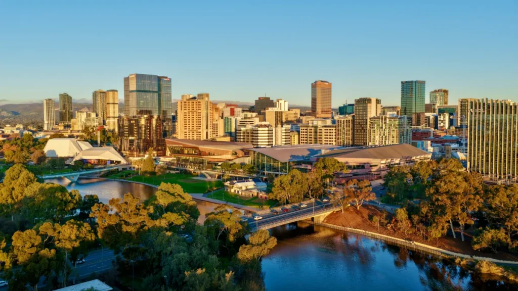 Adelaide skyline and convention centre beside the River Torrens, viewed across surrounding parkland.