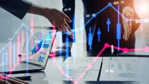 Awbury expands into Japan's credit and financial risk market Business professionals review financial charts on a laptop and tablet as blue and pink market graphs overlay the scene.
