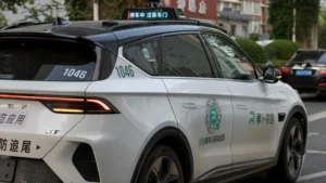 Beijing court, regulator and insurers’ body map autonomous driving liability disputes A white autonomous-driving taxi marked with Chinese text travels along a city street.