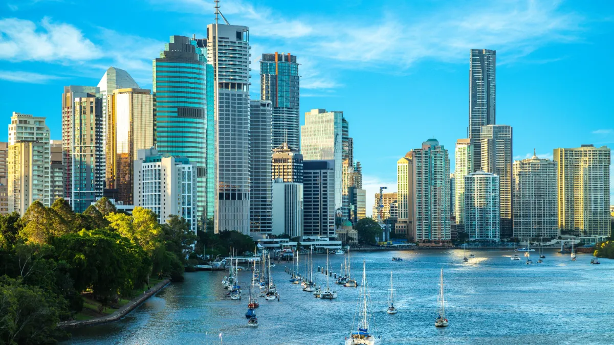 High-rise city skyline overlooking a marina and waterfront under a bright blue sky.