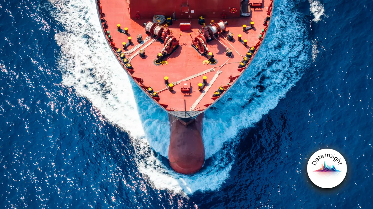 Aerial view of a cargo ship cutting through deep blue ocean water.