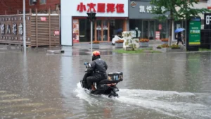 China’s nat cat economic losses near US$30bn in first nine months of 2026 A scooter rider navigates a flooded street in heavy rain in China.
