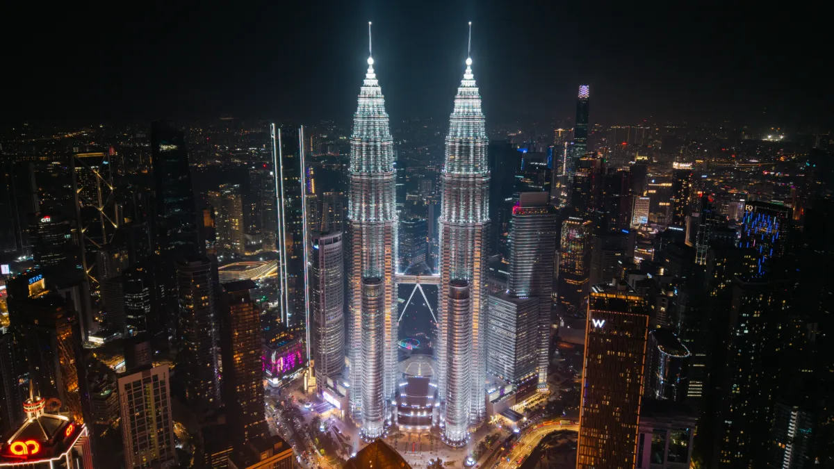 Kuala Lumpur's illuminated Petronas Twin Towers rise above the city skyline at night.