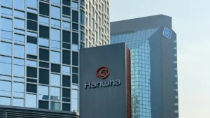 Hanwha Investment & Securities to enter Japan with GI Capital Management stake acquisition Hanwha logo and sign on a modern office building, with glass skyscrapers visible in the background.