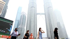 Masked pedestrians walk in front of Kuala Lumpur’s Petronas Twin Towers.