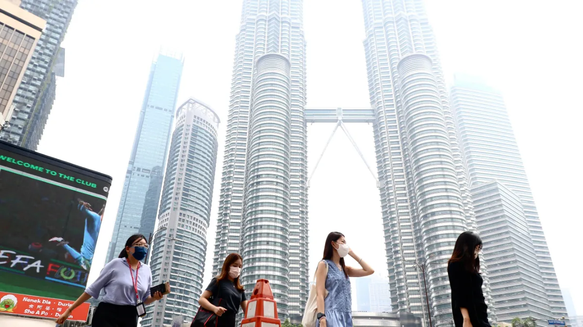 Masked pedestrians walk in front of Kuala Lumpur’s Petronas Twin Towers.