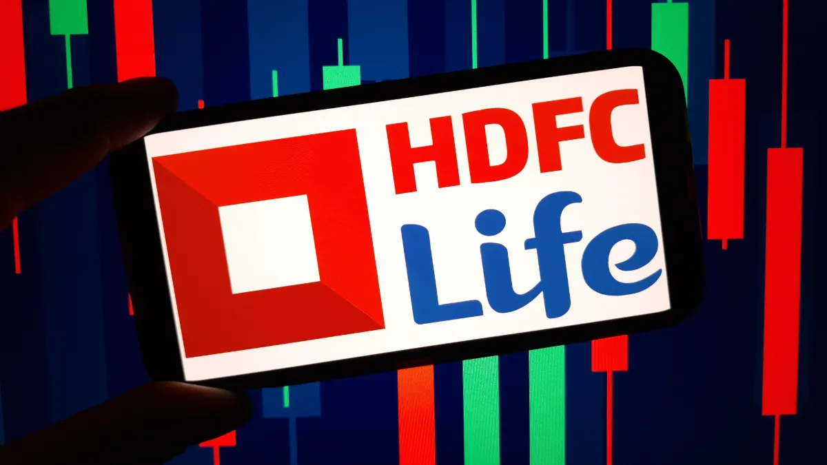 HDFC Life logo displayed on a smartphone against a background of red and green stock market candlesticks.