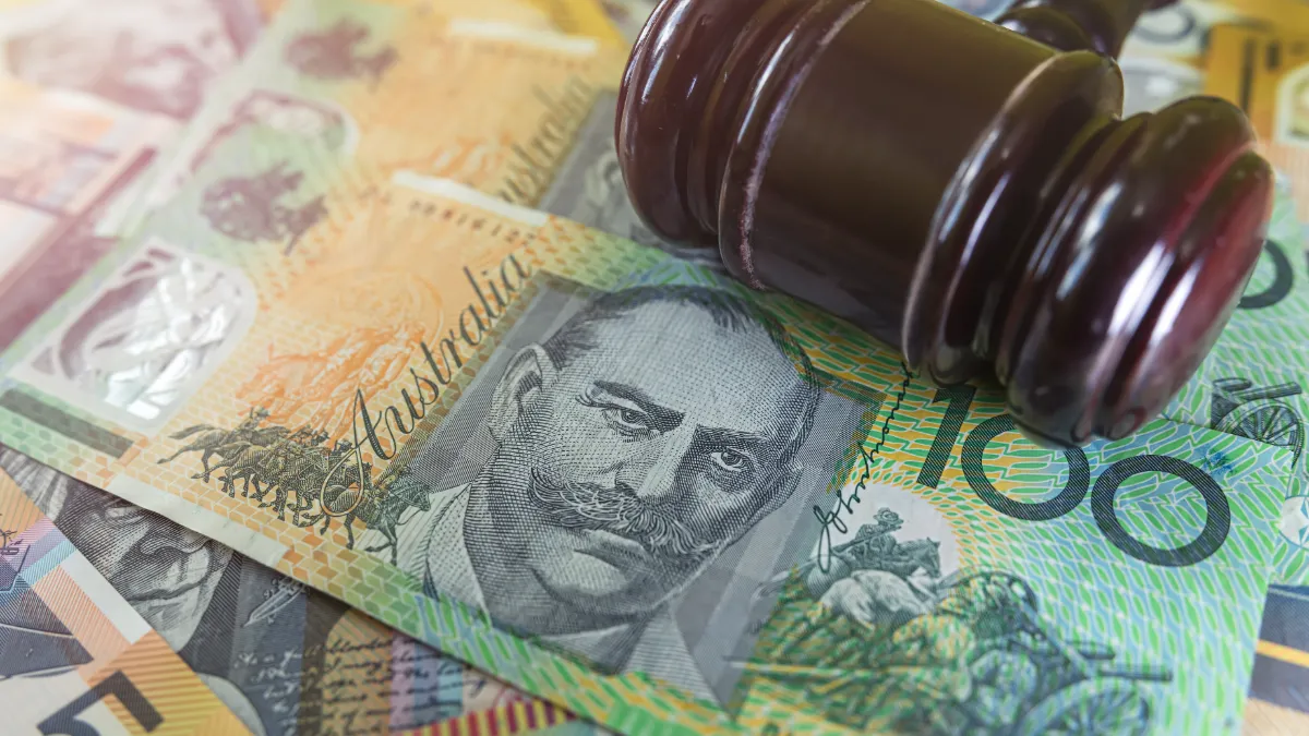 A wooden gavel rests on Australian dollar banknotes.