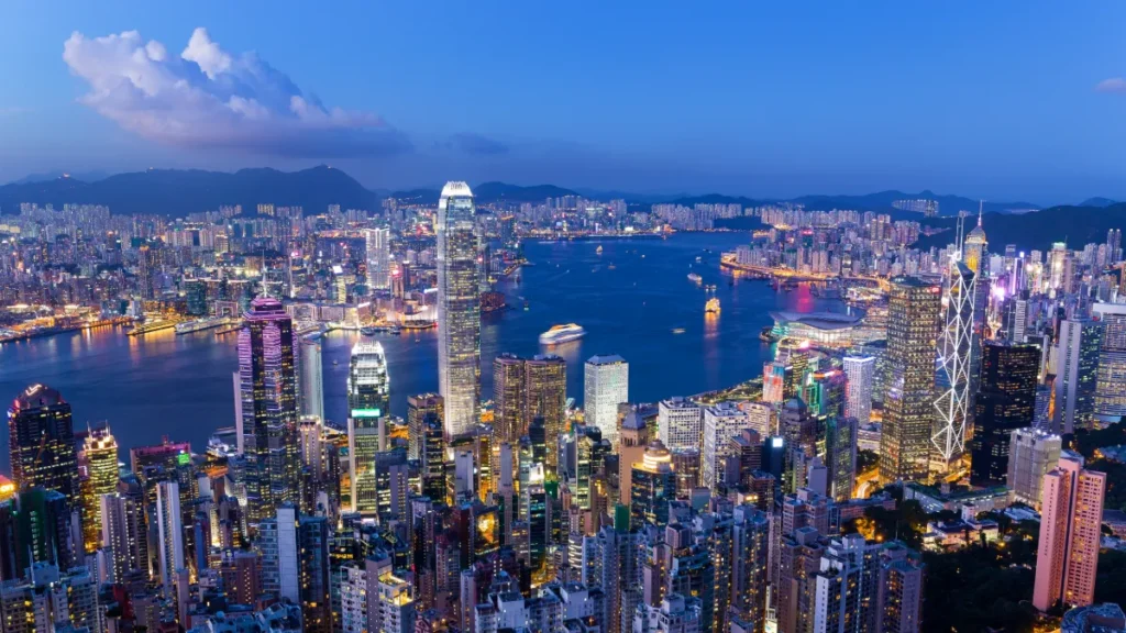 Hong Kong’s illuminated skyline and Victoria Harbour at twilight, viewed from above.