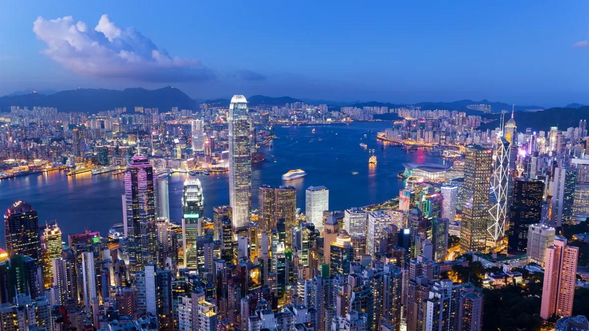 Hong Kong’s illuminated skyline and Victoria Harbour at twilight, viewed from above.