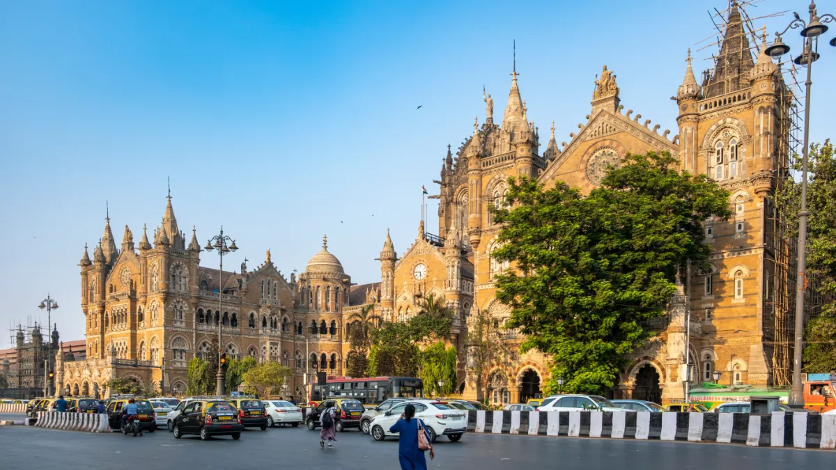 Mumbai’s ornate Chhatrapati Shivaji Terminus stands behind traffic on a busy city road.