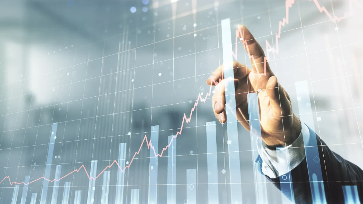 Hand touching a rising financial chart overlaid on bar graphs.