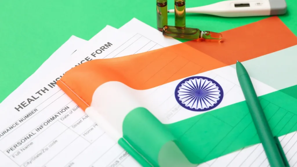 Indian flag draped over a health insurance form beside a green pen.