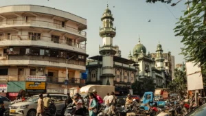 IRDAI mulls early-2027 implementation for distribution reforms Busy Indian street with motorcycles, cars and pedestrians outside an ornate mosque with domes and minarets.
