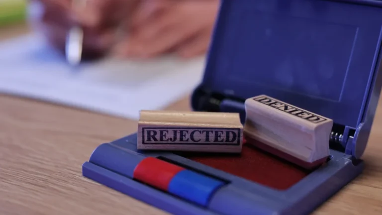 A rubber stamp marked “REJECTED” rests on an open blue stamp pad.