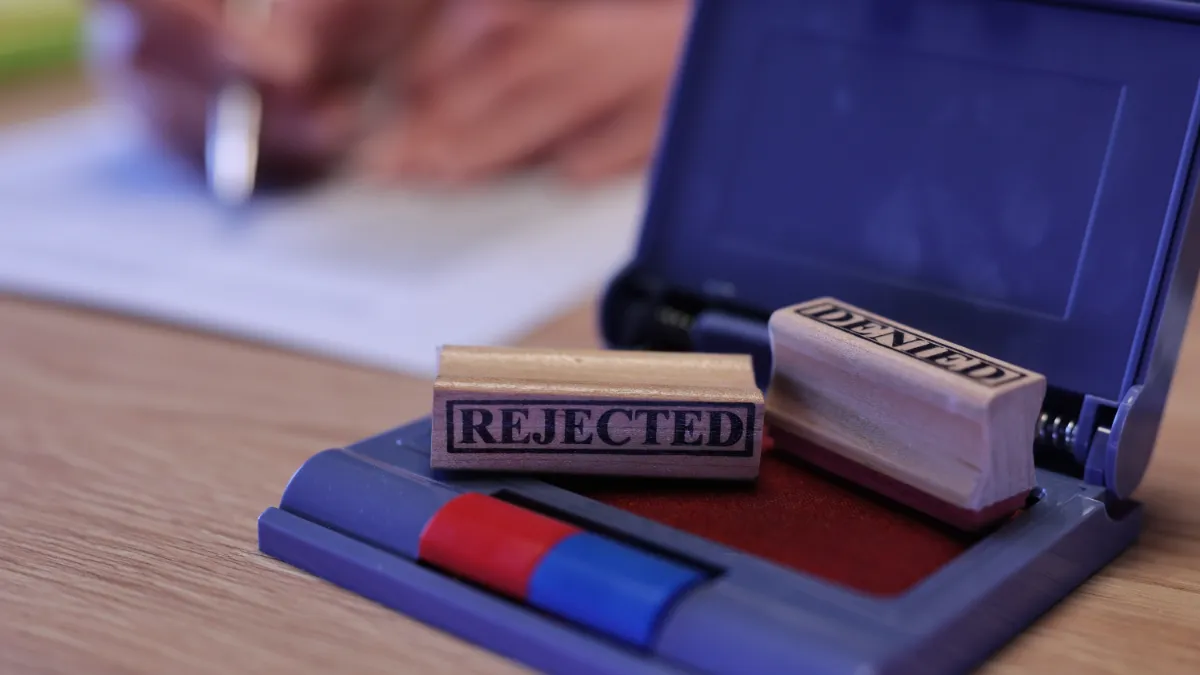 A rubber stamp marked “REJECTED” rests on an open blue stamp pad.