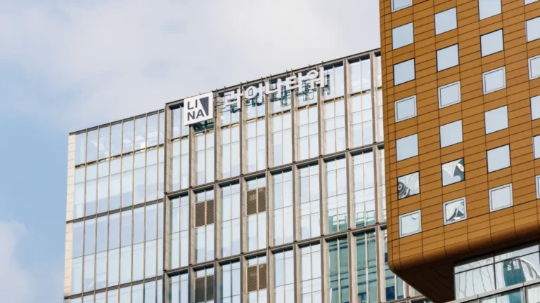 Modern office building bearing the LINA logo, with glass façades and an adjoining orange-clad tower.