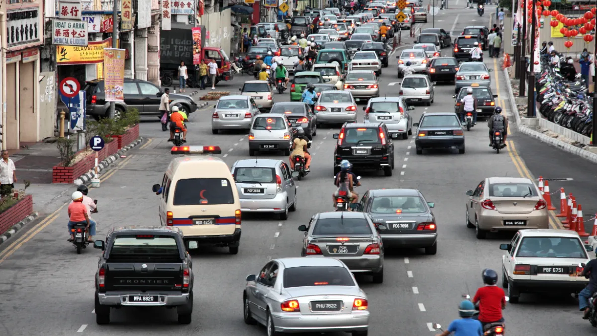 Busy Malaysian city street filled with cars, taxis and motorcycles.