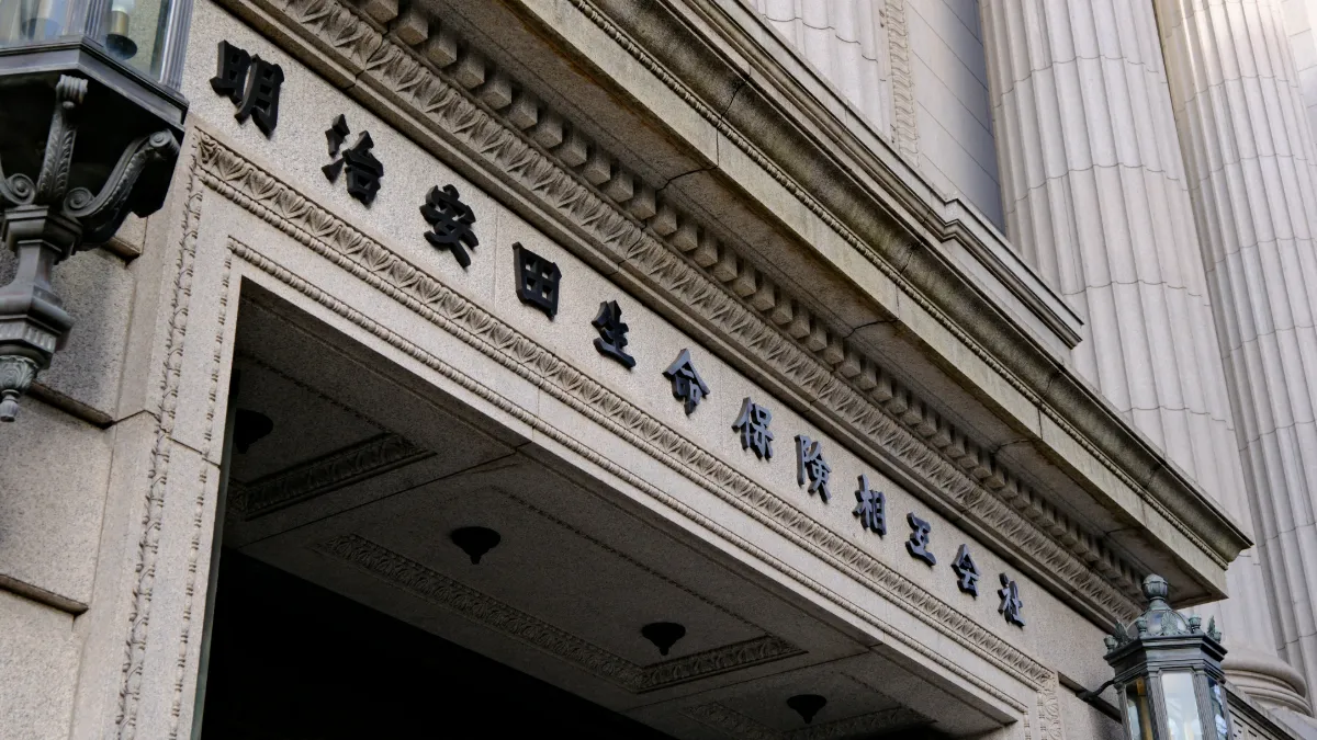 Meiji Yasuda Life Insurance Company building entrance with Japanese lettering on its stone façade.