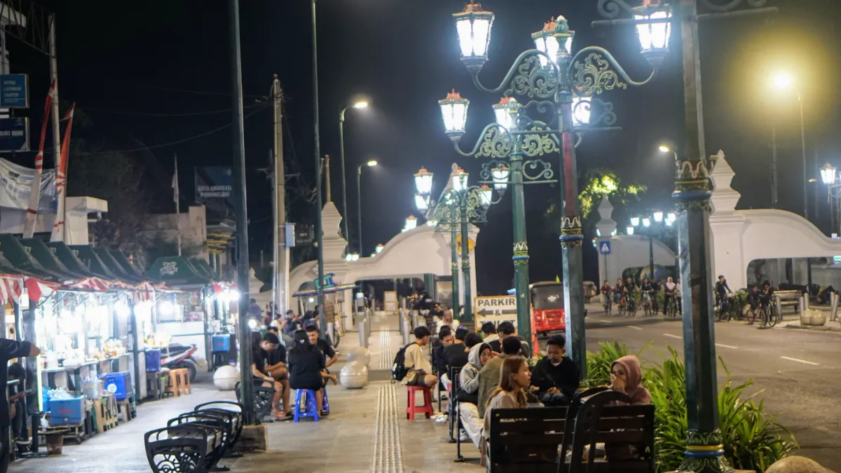 Night market stalls and diners line a street beneath ornate, brightly lit street lamps.