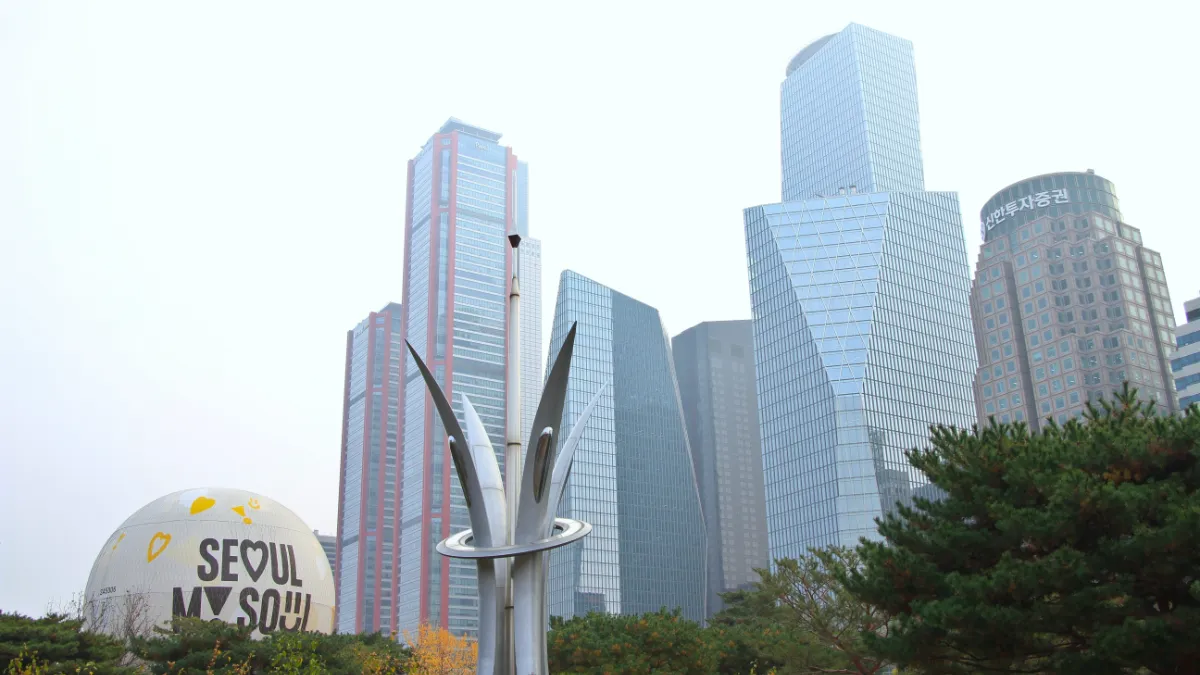 Seoul skyline with modern office towers and a “Seoul My Soul” sculpture in the foreground.