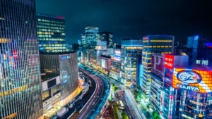 Pacific Life Re closes second Japan structured reinsurance deal of 2026 Nighttime Tokyo cityscape with illuminated Japanese signs, high-rises and curving multilane traffic.