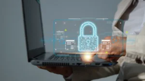 Person using a laptop displaying a holographic padlock and cybersecurity interface.