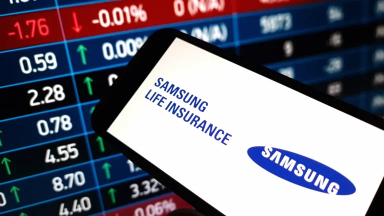 Samsung Life Insurance logo displayed on a smartphone over a stock market board.