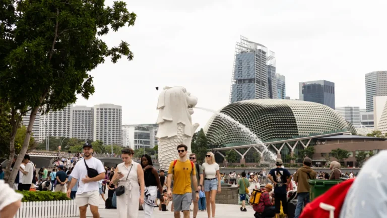 Crowds gather near Singapore’s Merlion and Esplanade concert hall, with the city skyline behind them.