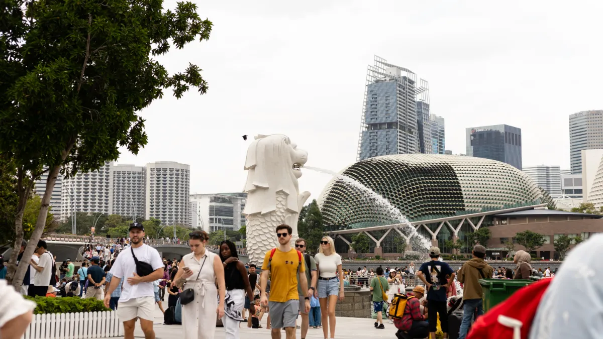 Crowds gather near Singapore’s Merlion and Esplanade concert hall, with the city skyline behind them.