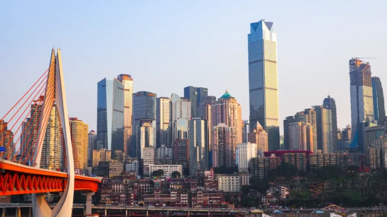 A cable-stayed bridge stands before a dense skyline of high-rise buildings.