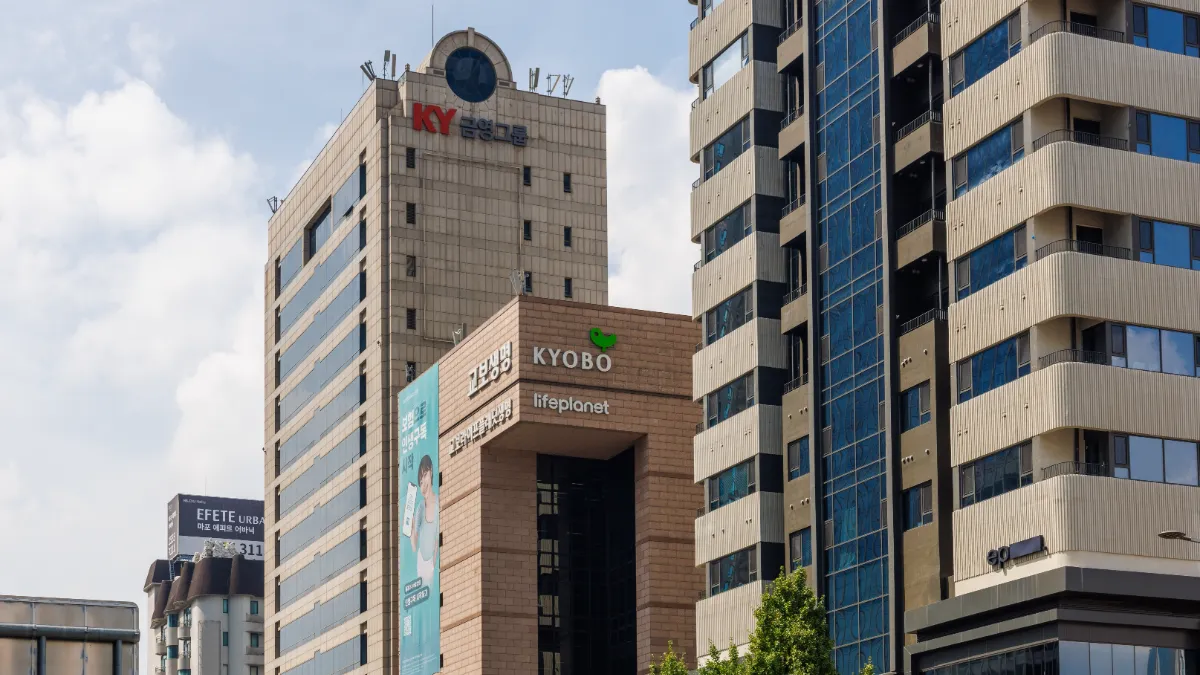 Seoul commercial buildings bearing Kyobo and Lifeplanet signs against a partly cloudy sky.