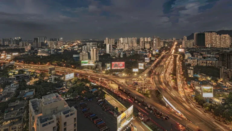 Nighttime cityscape with high-rise buildings, illuminated highways and heavy traffic.