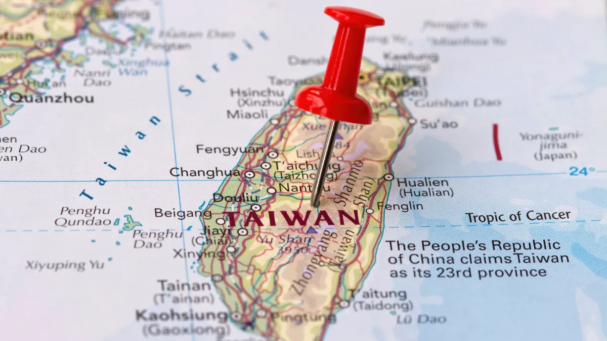 A red pushpin marks Taiwan on a map, with nearby cities and surrounding waters labeled.