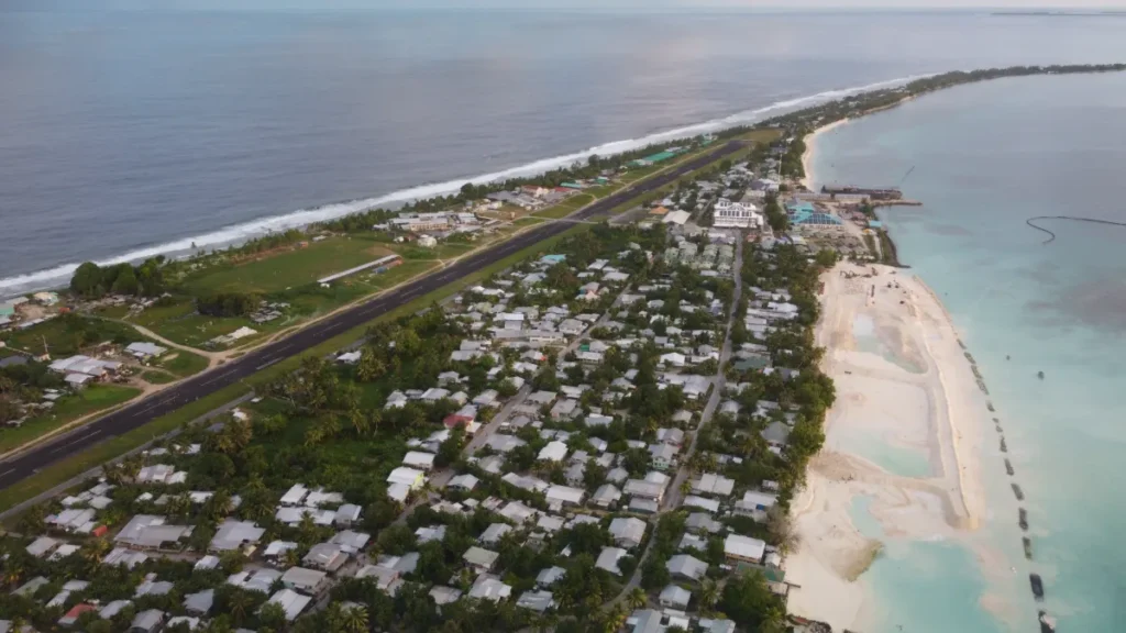 Aerial view of Tuvalu showing a narrow island, runway, homes, beach and lagoon.
