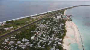 Aerial view of Tuvalu showing a narrow island, runway, homes, beach and lagoon.