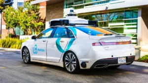 Allianz, Ping An P&C named inaugural partners in WeRide’s global insurance programme A WeRide autonomous car with roof-mounted sensors parked outside a modern building.